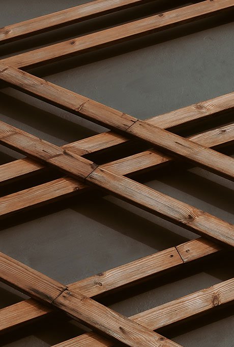 Celosía de listones de madera entrecruzados sobre una pared gris